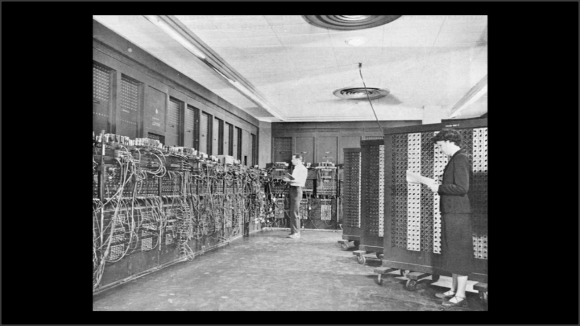 Foto, en blanco y negro, de una pared llena de interruptores y cables